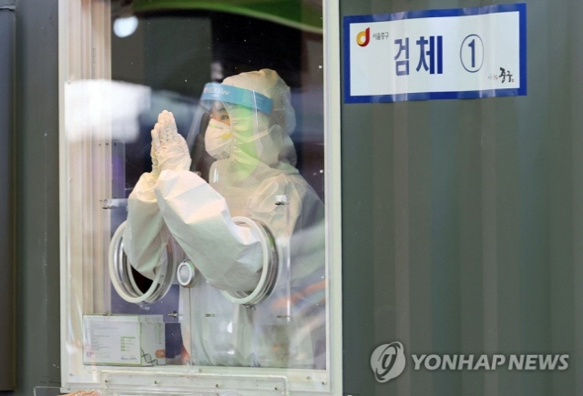 31일 오후 서울역 광장에 마련된 신종 코로나바이러스 감염증(코로나19) 임시 선별 검사소에서 한 의료진이 잠시 손을 모아 추위를 녹이고 있다./연합뉴스