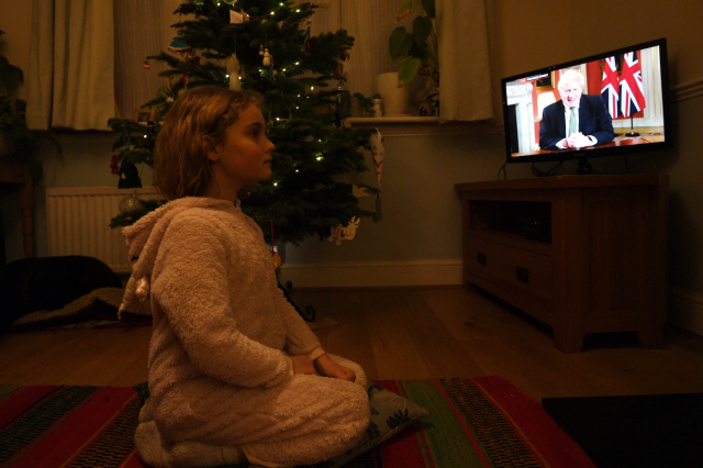 4일(현지시간) 영국 런던에서 7살 아이가 보리스 존슨 영국 총리의 대국민 TV 연설을 시청하고 있다. 존슨 총리는 이날 코로나19 확산을 막기 위해 3차 봉쇄조치를 내리겠다고 발표했다./EPA연합뉴스
