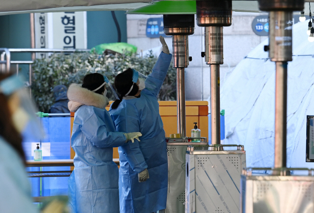 지난 31일 서울역 임시선별진료소에서 의료진이 추위를 녹이고 있다./성형주기자