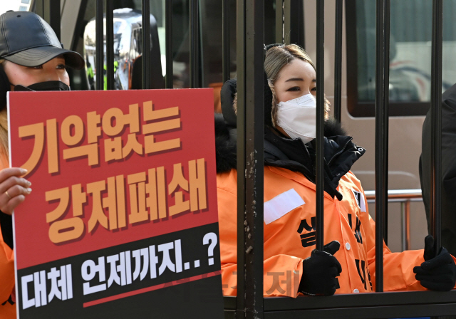 필라테스 피트니스 사업자 연맹 관계자들이 7일 서울 여의도 더불어민주당사 앞에서 ‘실내체육시설’이라는 글씨가 적힌 수의복을 입고 생존권 보장을 요구하는 집회를 열고 있다. 이날 정부가 내일(8일)부터 신종 코로나바이러스 감염증(코로나19) 방역 대책 차원에서 영업금지 조처를 내렸던 모든 실내체육시설에 사용 인원을 9명으로 제한하는 조건으로 운영을 허용하기로 했다. 다만 이용 대상을 아동·청소년으로 제한하고, 운영 목적도 교습으로만 한정해 성인 헬스장 들은 여전히 영업을 재개할 수 없어서 논란이 예상된다./권욱기자 2021.01.07