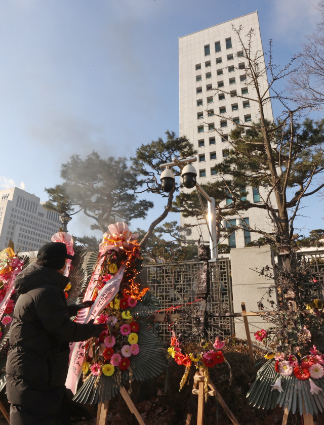 지난 5일 오전 서울 서초구 대검찰청 앞에서 한 남성이 윤석열 검찰총장 응원화환에 불을 붙이자 대검 보안요원이 달려와 불을 끄고 있다./연합뉴스