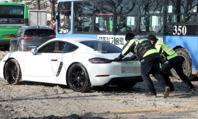 밤사이 폭설이 내린 지난 7일 오전 서울 시내에서 경찰들이 미끄러지는 차량을 밀어주고 있다./연합뉴스