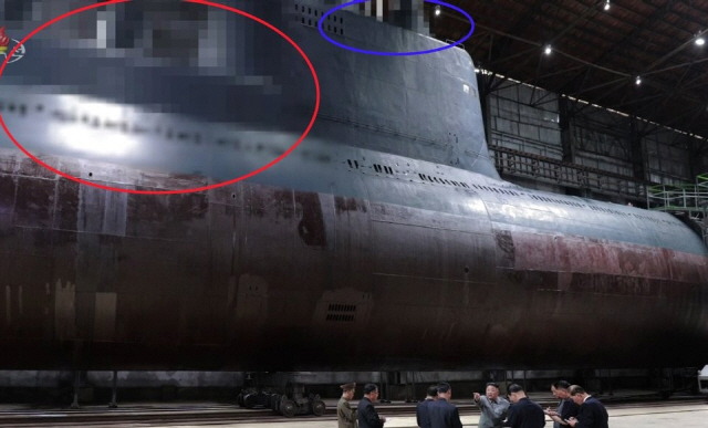 지난해 7월 북한 조선중앙TV가 “김정은 국무위원장이 새로 건조한 잠수함을 시찰했다”고 보도하면서 공개한 잠수함 모습. 당시 조선중앙TV는 시찰 장면이 담긴 사진을 공개하면서 잠수함발사탄도미사일(SLBM) 발사관이 위치했을 것으로 추정되는 부분(붉은 원)과 함교탑 위 레이더와 잠망경 등이 위치했을 것으로 추정되는 부분(파란 원)을 각각 모자이크 처리했다.              /연합뉴스