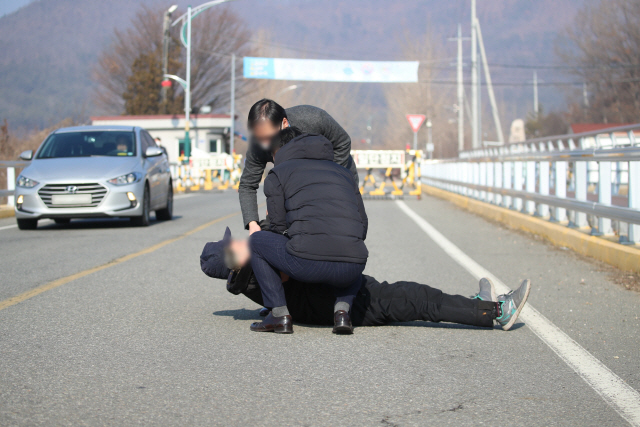 경북 청송군 경북북부제2교도소에 지난해 12월 28일 한 주민이 서울동부구치소 코로나19 확진 수감자들의 이송을 반대하며 도로에 드러누워 있다. /청송=연합뉴스