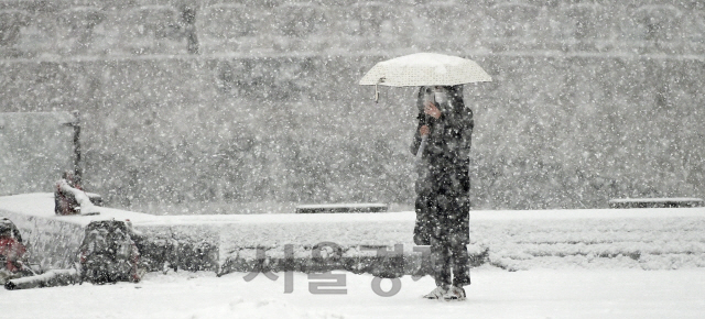 서울 일부 지역을 비롯한 전국 곳곳에 대설 특보가 내려진 12일 오후 많은 눈이 내리는 서울 종로구 세종대로에서 한 시민이 잠시 발걸음을 멈추고 도심의 설경을 스마트폰에 담고 있다./오승현기자 2021.01.12