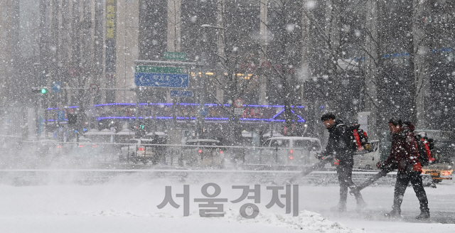 서울 일부 지역을 비롯한 전국 곳곳에 대설 특보가 내려진 12일 오후 많은 눈이 내리는 서울 종로구 청계광장에서 관계자들이 긴급 제설작업을 하고 있다./오승현기자 2021.01.12