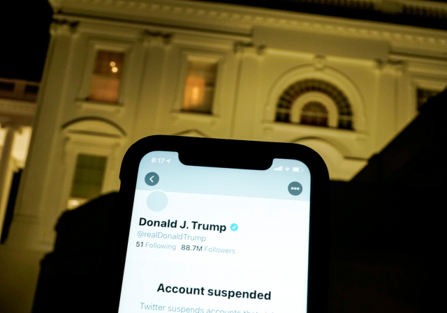 도널드 트럼프 미국 대통령의 계정이 폐쇄됐다고 알리는 스마트폰 화면 뒤로 백악관이 보이고 있다./로이터연합뉴스
