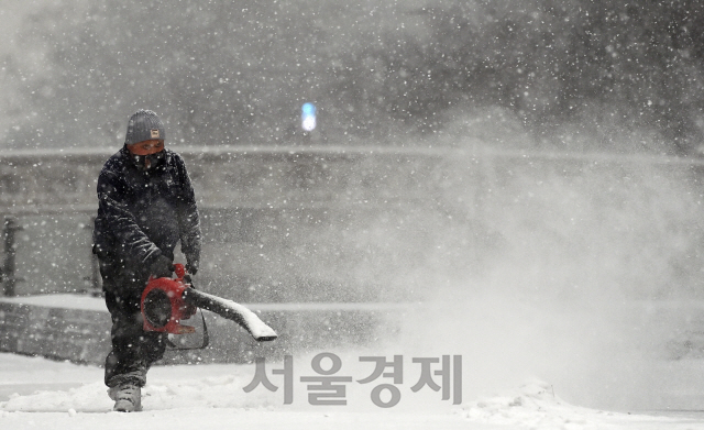 서울 일부 지역을 비롯한 전국 곳곳에 대설 특보가 내려진 12일 오후 많은 눈이 내리는 서울 종로구 청계광장에서 관계자들이 긴급 제설작업을 하고 있다./오승현기자 2021.01.12