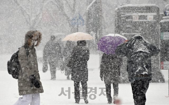 서울 일부 지역을 비롯한 전국 곳곳에 대설 특보가 내려진 12일 오후 많은 눈이 내리는 서울 종로구 세종대로에서 시민들이 퇴근길 발걸음을 재촉하고 있다./오승현기자 2021.01.12