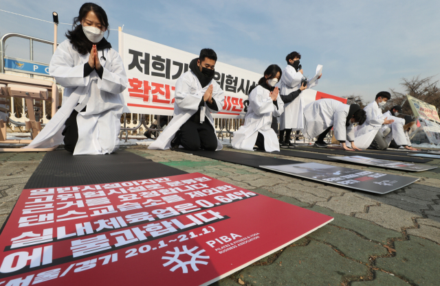 12일 서울 여의도 국회 앞에서 필라테스·피트니스 사업자연맹 관계자들이 실내체육시설 집합금지 해제, 영업 재개를 요구하며 소복 차림으로 999배를 하고 있다./연합뉴스