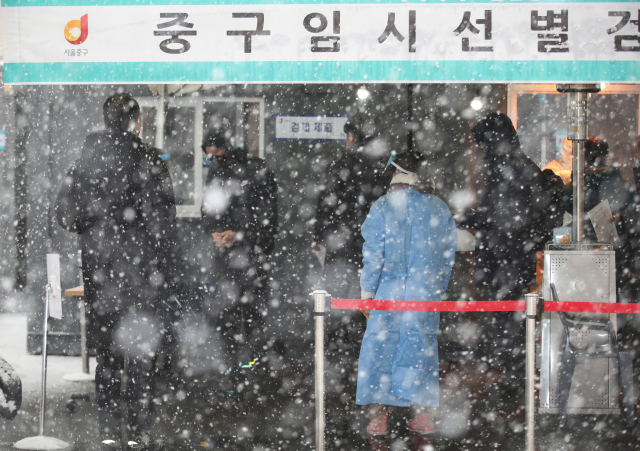 눈이 내린 12일 오후 서울역 광장에 마련된 코로나19 임시 선별검사소에서 시민들이 검사를 받고 있다./연합뉴스