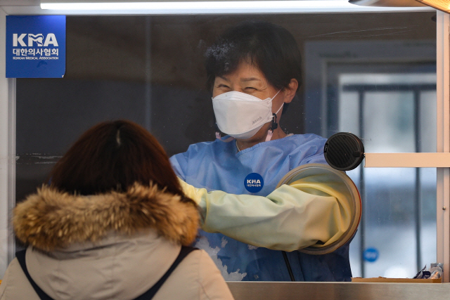 15일 오후 서울시청 앞에 마련된 임시선별진료소에서 의료진이 코로나19 검사를 하며 웃음을 짓고 있다./연합뉴스