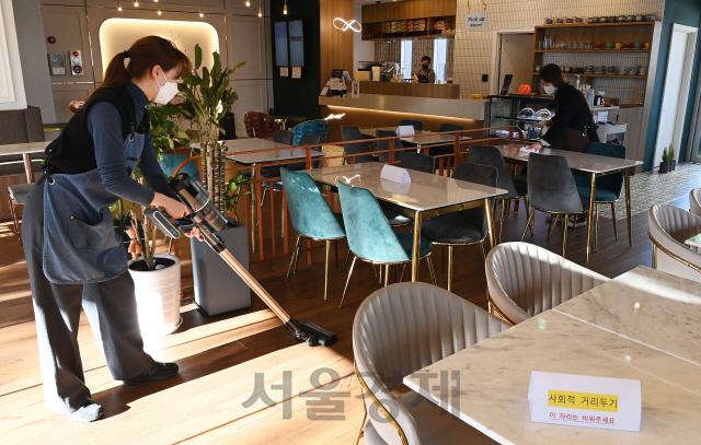 정부가 현행 사회적 거리두기 단계(수도권 2.5단계·비수도권 2단계)와 5인 이상 사적모임 금지 조치를 이달 말까지 2주간 연장한다. 다만 18일 부터는 유흥시설과 홀덤펍을 제외한 집합금지 업종의 세부적 방역 조치가 완화돼 카페는 오후 9시까지 매장 내 취식이 허용되고 수도권 내 헬스장 등 실내체육시설과 노래연습장은 8㎡당 1명으로 인원을 제한하는 조건 하에 문을 연다. 17일 오전 경기도 고양시의 한 카페에서 업주와 가족이 매장 곳곳을 소독 및 청소하며 손님 맞을 준비를 하고 있다./고양=오승현기자 2021.01.17