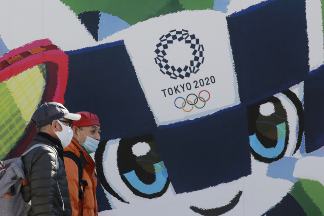 일본이 신종 코로나바이러스 감염증(코로나19) 확산으로 비상인 가운데 19일 도쿄에서 시민들이 도쿄올림픽·패럴림픽 홍보 포스터 앞을 지나가고 있다./연합뉴스
