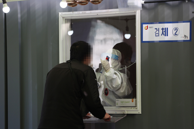 지난 24일 오후 서울역광장에 설치된 임시선별진료소에서 의료진이 검체를 채취하고 있다./연합뉴스
