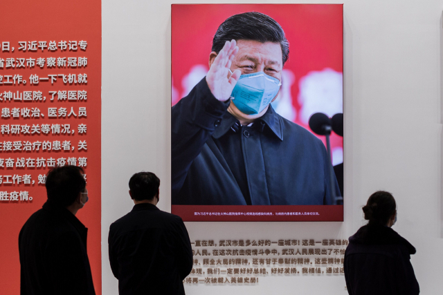 지난 15일 중국 후베이성 우한의 한 코로나19 방역 전시회에서 방문객들이 시진핑 중국 국가주석의 사진을 살펴보고 있다. /AFP연합뉴스