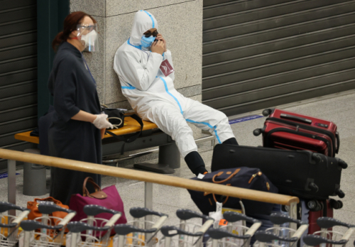 3일 오후 인천국제공항 제1여객터미널을 통해 입국한 중국인이 방역복을 착용한 채 경찰 인솔을 받아 자가격리 시설로 이동하기 전 대기하고 있다. /연합뉴스