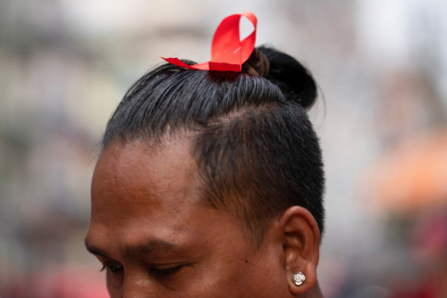 미얀마 최대 도시 양곤에서 한 남성이 아웅산 수치 고문이 이끄는 정당을 상징하는 빨간색 리본을 머리에 꽂고 쿠데타에 대한 저항운동을 하고 있다./연합뉴스