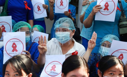 지난 5일 미얀마 양곤의 양곤 교육대 캠퍼스 앞에 교사들이 모여 '미얀마 교사들, 시민 불복종'이라고 쓰인 팻말을 들고 세 손가락을 들어 저항의 표시를 하고 있다./연합뉴스