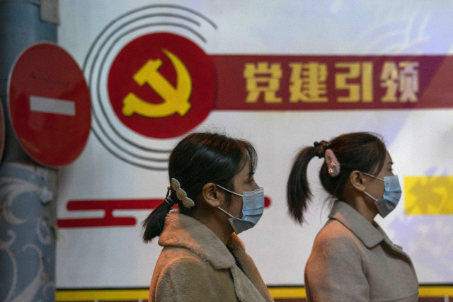 중국 베이징에서 공산당 슬로건 아래로 시민들이 지나가고 있다. /AP연합뉴스