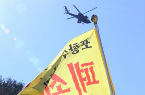 지난 4일 경북 포항시 남구 장기면 수성사격장 앞에서 인근 주민들이 사격훈련 중단을 요구하는 집회를 하고 있는 가운데 아파치 헬기가 비행을 하고 있다. /포항=연합뉴스