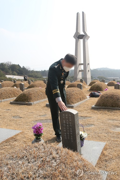한 영관급 현역 군인이 지난 19일 광주 국립 5·18민주묘지에서 고(故) 홍남순 변호사의 묘소를 참배한 뒤 묘비를 어루만지고 있다. /연합뉴스