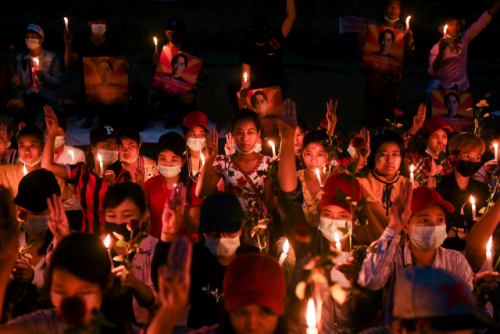 군부 쿠데타 발생 후 유혈사태가 악화하는 미얀마 양곤에서 21일(현지시간) 시위대가 독재에 대한 저항의 상징으로 '세 손가락 경례'를 하며 촛불시위를 벌이고 있다. 현지 매체 이라와디는 제2 도시 만달레이 등지에서 전날 밤 군경의 무차별 총격으로 최소 4명이 숨지고, 100명 이상이 부상했다고 보도했다. /연합뉴스