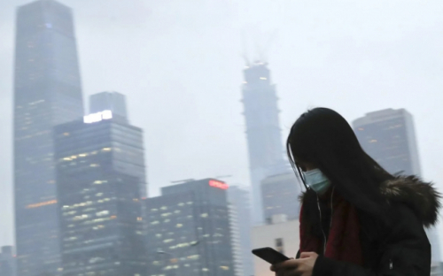 미세먼지에 둘러싸인 중국 베이징 중심가에서 한 여성이 스마트폰을 사용하고 있다. /SCMP