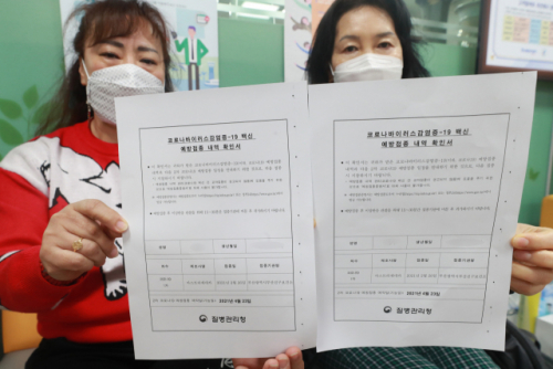 26일 부산 진구 보건소에서 백신 접종을 마친 한 요양원 종사자들이 접종 확인서를 들어 보이고 있다. /연합뉴스