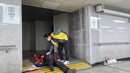 지난 2일 다시서기종합지원센터 직원이 서울역 인근 지하도에서 노숙인에게 마스크와 핫팩을 건네고 있다. /강동헌 기자