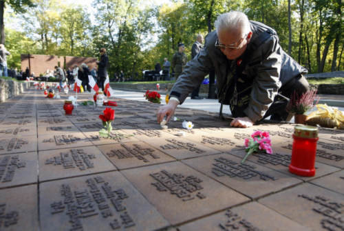 폴란드 출신의 한 남성이 우크라이나 하르키우에서 2차 세계대전 도중 소련군에 의해 사망한 폴란드 장교들을 추모하며 기념비에 초를 켜고 있다./EPA연합뉴스