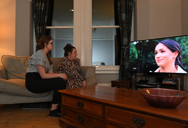 영국 리버풀에 거주하는 주민들이 지난 8일(현지시간) 해리 왕자와 메건 마클 왕자비가 유명 방송인 오프라 윈프리가 진행하는 CBS방송 프로그램에 출연해 인터뷰를 하는 모습을 지켜보고 있다./AFP연합뉴스