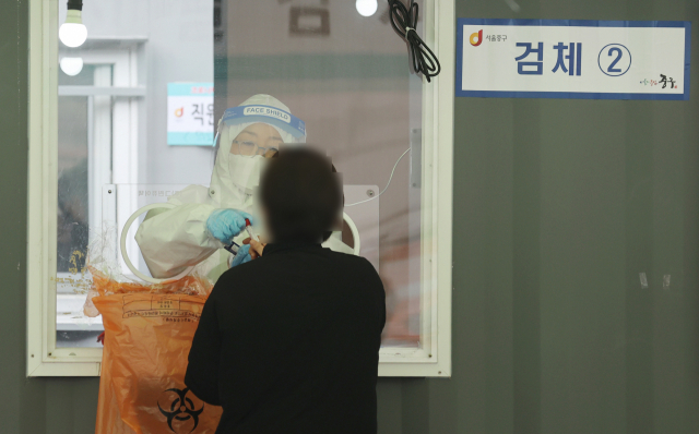 12일 서울역 광장에 마련된 임시 선별검사소를 찾은 시민이 코로나19 검사를 받고 있다./연합뉴스