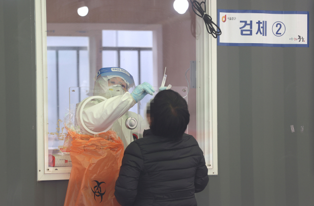 지난 13일 오전 서울역광장에 마련된 임시선별진료소에서 의료진이 검체를 채취하고 있다./연합뉴스
