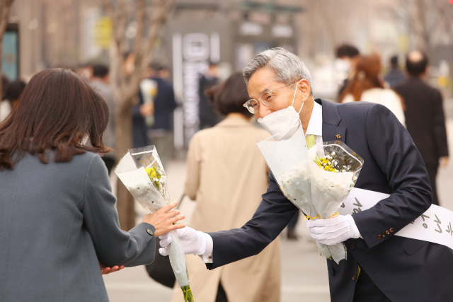 윤종규(오른쪽) KB금융 회장이 15일 서울 여의도역 인근에서 출근길 시민들에 꽃다발을 전달하고 있다. /사진 제공=KB금융