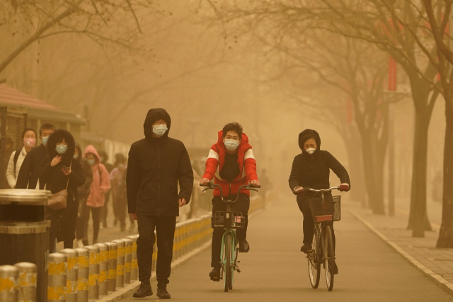 중국 베이징의 주민들이 15일 오전 황사로 뒤덮인 거리를 걷고 있다. 베이징시 기상대는 이날 올해 들어 처음으로 황사 황색경보를 발령했다./AP연합뉴스