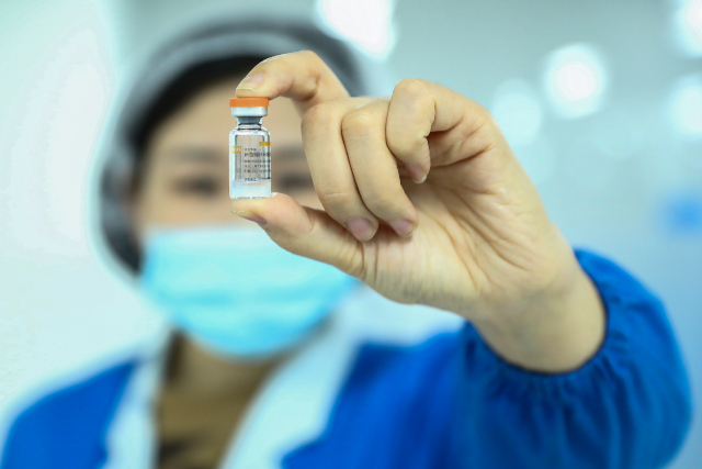 지난해 12월 23일 베이징 시노백사에서 직원이 자사가 개발한 코로나19 백신을 들어 보이고 있다./연합뉴스