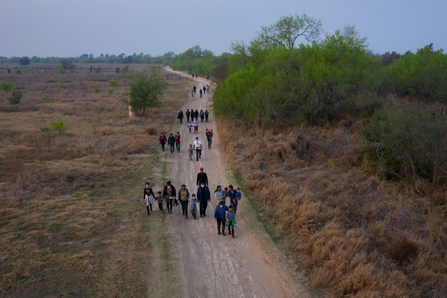 중앙아메리카에서 미국에 온 불법 이민자들이 지난 17일(현지 시간) 텍사스의 국경 지대 페니타스의 흙길을 걷고 있다. 이들은 뗏목을 타고 리오그란데강을 건넜다. /로이터연합뉴스