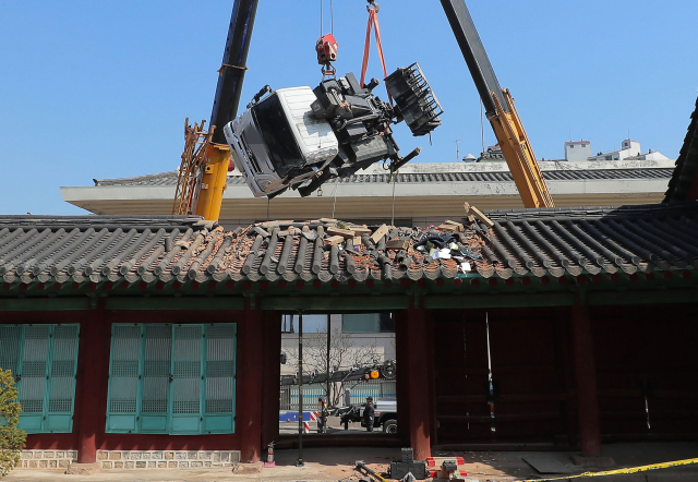 지난 8일 서울 종로구 성균관 문묘 동삼문 지붕 위로 떨어진 사다리차를 대형 크레인이 들어내고 있다. 이날 사고는 문묘 은행나무 가지치기 작업을 위해 크레인차로 사다리차를 들어 문묘 내부로 옮기던 중 발생했다./연합뉴스