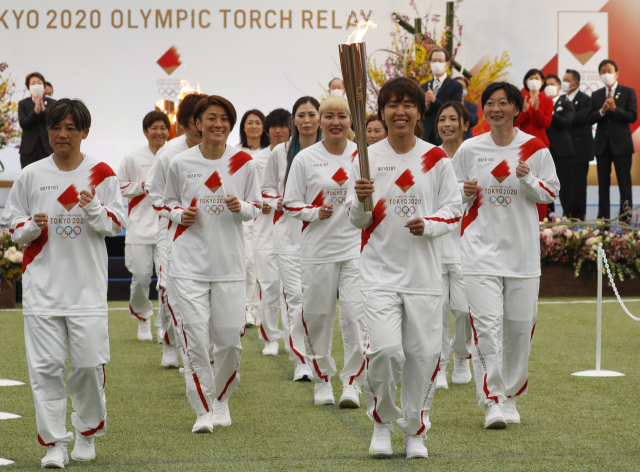 일본 여자 축구 대표팀 선수들이 25일 일본 후쿠시마현에서 열린 도쿄올림픽 성화 출발식에서 첫 주자로 성화 봉송을 시작하고 있다. 코로나19 확산 우려에 올림픽조직위원회는 성화 봉송을 인터넷 생중계로 봐달라고 당부했다. /AP연합뉴스