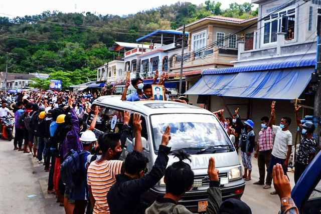 미얀마 남단 꼬따웅에서 28일(현지시간) 주민들이 전날 군부 쿠데타 규탄 시위 도중 군경이 쏜 총에 맞아 숨진 시위대의 장례 행렬을 향해 '세 손가락 경례'를 하고 있다. 세 손가락 경례는 독재에 대한 저항을 상징한다./AFP연합뉴스