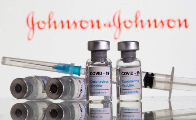 존슨앤드존슨사의 로고 앞에 놓인 코로나19 백신과 주사기의 모습./로이터연합뉴스