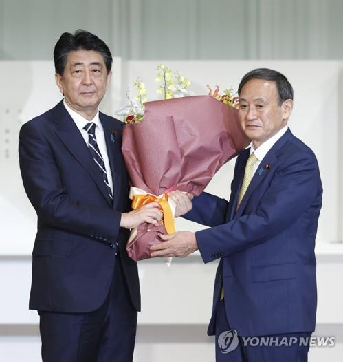작년 9월 자민당 총재 경선에서 승리한 스가 요시히데(菅義偉) 당시 관방장관이 물러나는 아베 신조 당시 총재(총리)에게 꽃다발을 건네고 있다. /교도연합뉴스