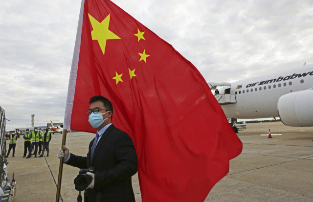 지난 2월 15일 아프리카의 짐바브웨 하라레 공항에서 열린 중국 시노팜 코로나19 백신 인도식에서 중국 관리가 국기인 오성홍기를 들고 있다. 이날 20만 도스의 백신이 짐바브웨에 도착했다. /AP연합뉴스