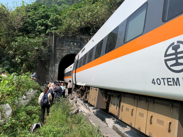 People walk next to a train which derailed in a tunnel north of Hualien, Taiwan April 2, 2021, in this handout image provided by Taiwan\'s National Fire Agency. Taiwan\'s National Fire Agency/Handout via REUTERS ATTENTION EDITORS - THIS IMAGE WAS PROVIDED BY A THIRD PARTY. NO RESALES. NO ARCHIVES.