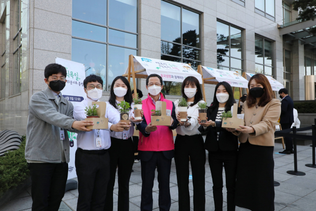 박춘원(왼쪽에서 네번째) 흥국생명 대표와 임직원들이 지난 5일 서울 종로구 본사 앞 해머링맨 광장에서 열린 ‘친환경 재활용 화분 나눔’ 행사에서 화분을 들고 있다. /사진 제공=흥국생명