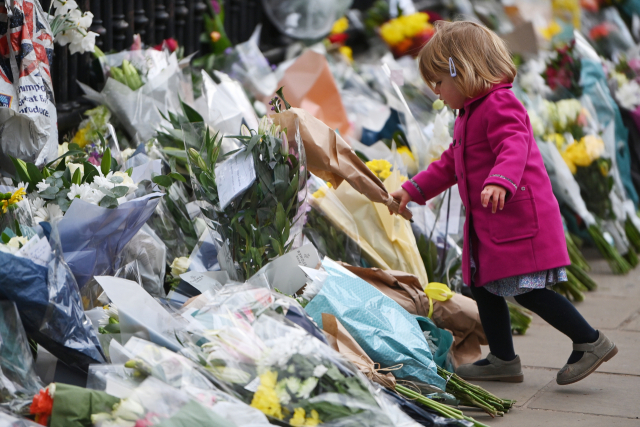 영국 런던 버킹엄궁 앞에 한 어린이가 필립공을 추모하는 꽃다발을 놓고 있다. /EPA연합뉴스