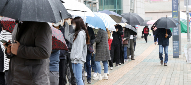 12일 오후 서울 중랑구 보건소에 마련된 코로나19 임시선별진료소를 찾은 시민들이 우산을 쓰고 순서를 기다리고 있다. /연합뉴스