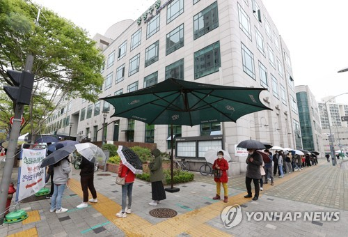 지난 12일 오후 서울 중랑구 보건소에 마련된 코로나19 임시선별진료소를 찾은 시민들이 우산을 쓰고 순서를 기다리고 있다./연합뉴스