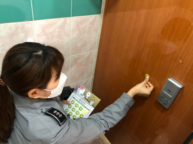 한 경찰관이 화장실 벽에 생긴 작은 구멍 위에 '포순이 손' 스티커를 붙이고 있다./사진제공=서울 송파경찰서